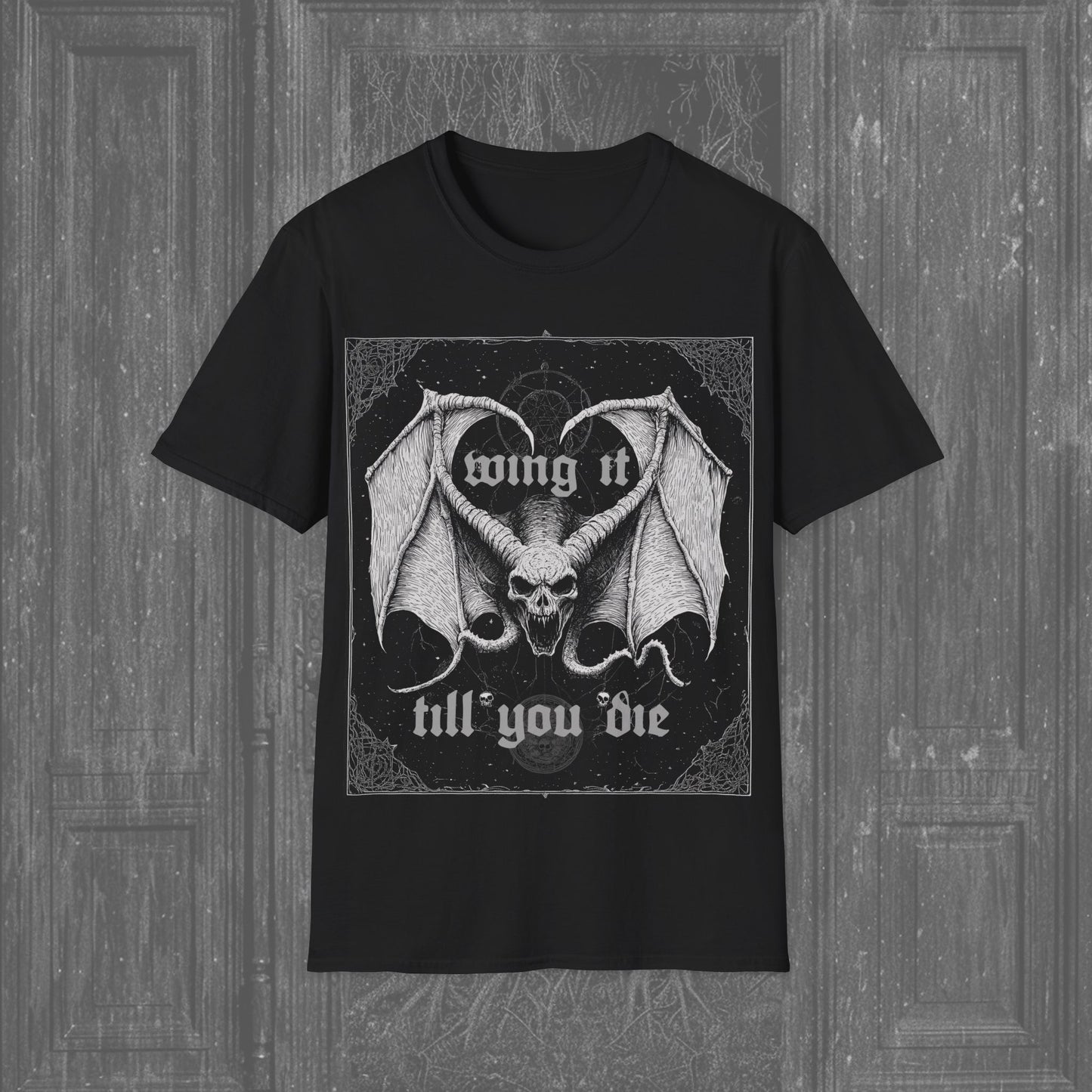 Black gothic t-shirt featuring a winged skull with the phrase "Wing It Till You Die" in gothic lettering, combining dark humor with macabre style.